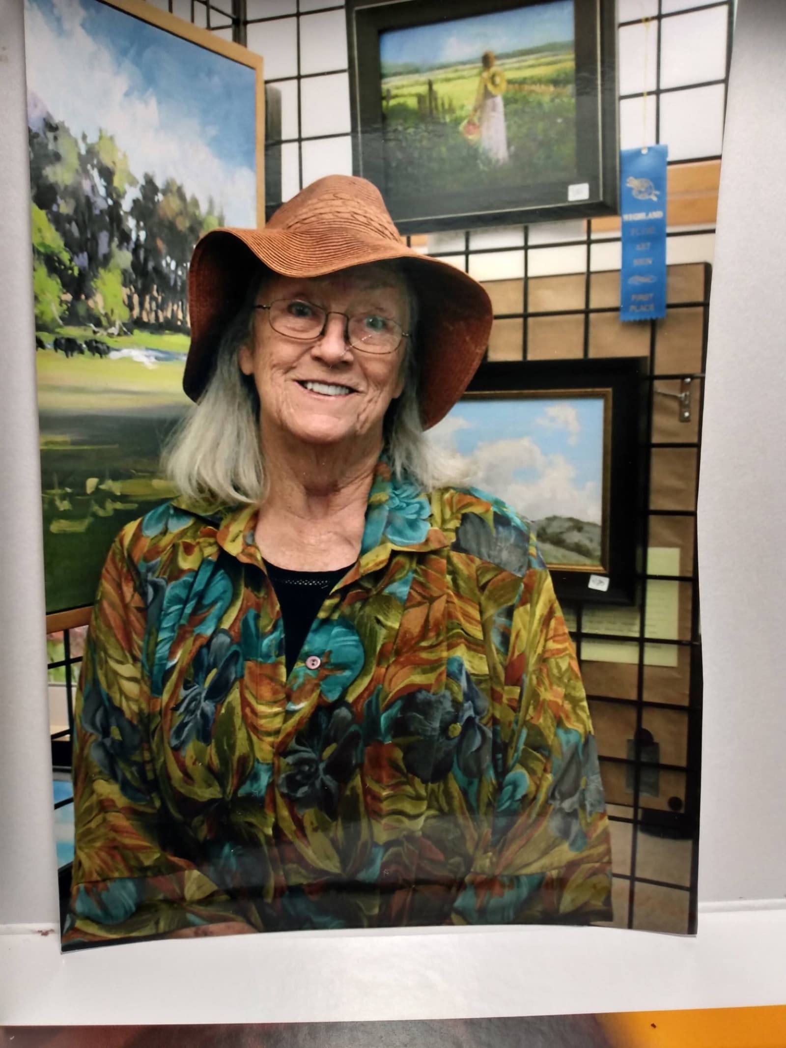 Linda Farrar surrounded by her landscape paintings at a gallery show