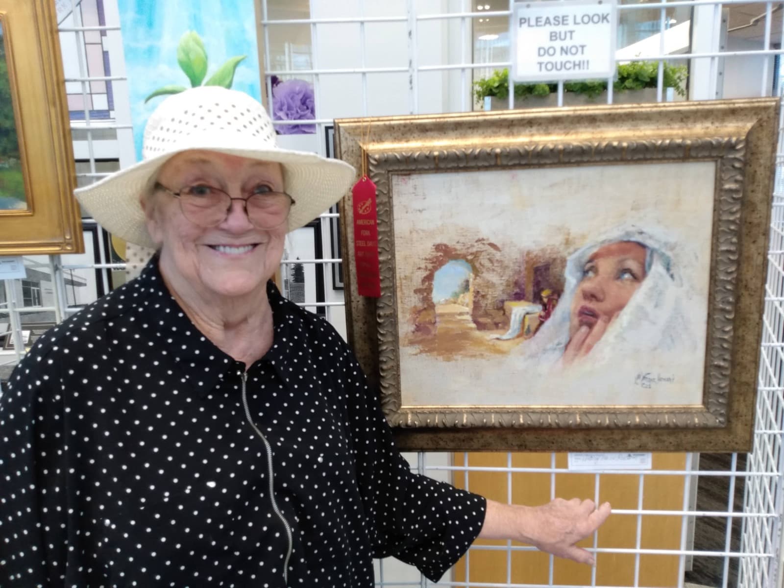 Linda Farrar smiling next to her award-winning painting at an art show